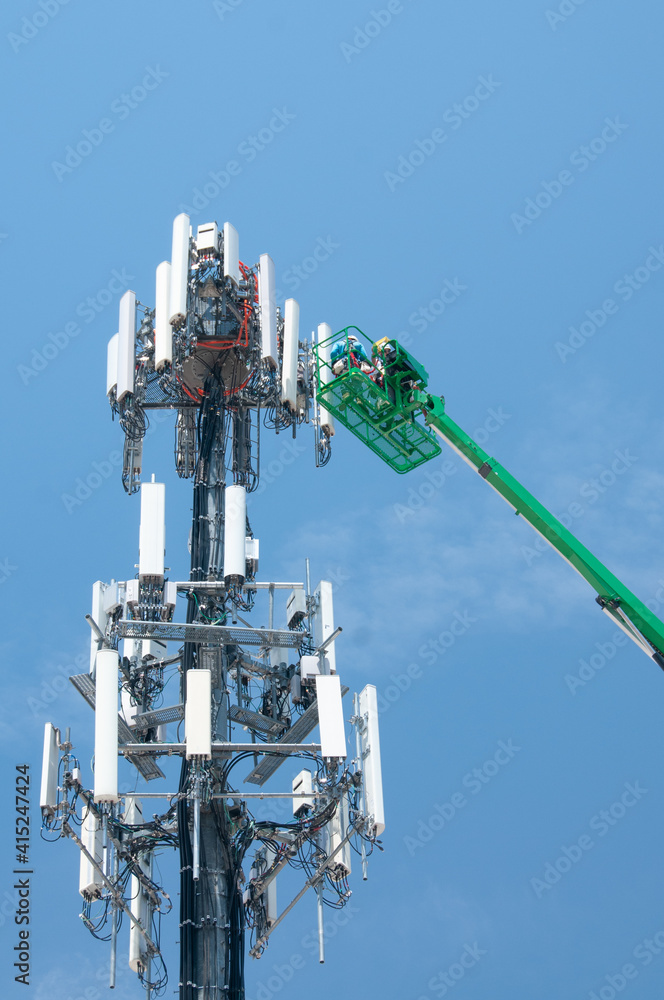 A work crew performs maintenance on a cell phone transmission tower. 