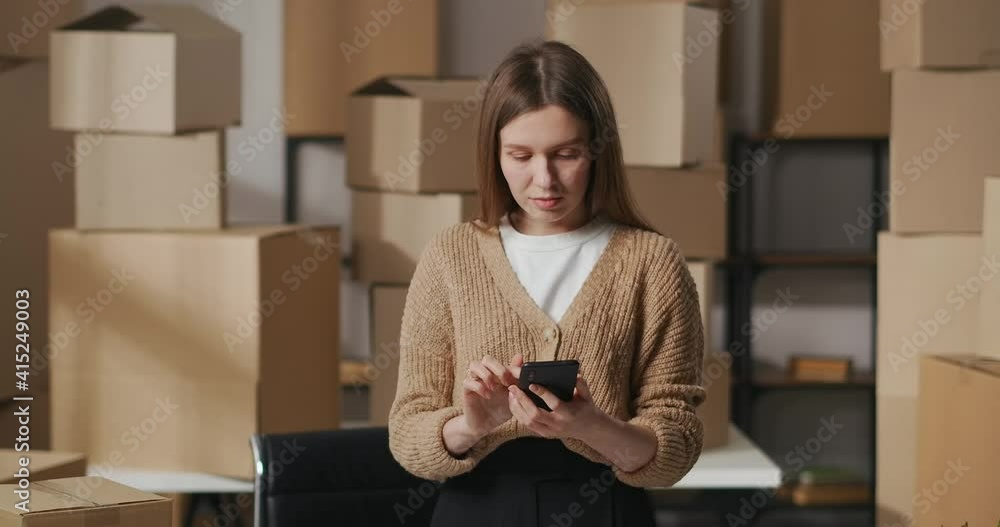 smm manager woman is communicating in online chat in social nets with clients, portrait in warehouse with boxes, small business smm manager woman is communicating in online chat in social nets with clients, portrait in warehouse with boxes, small business