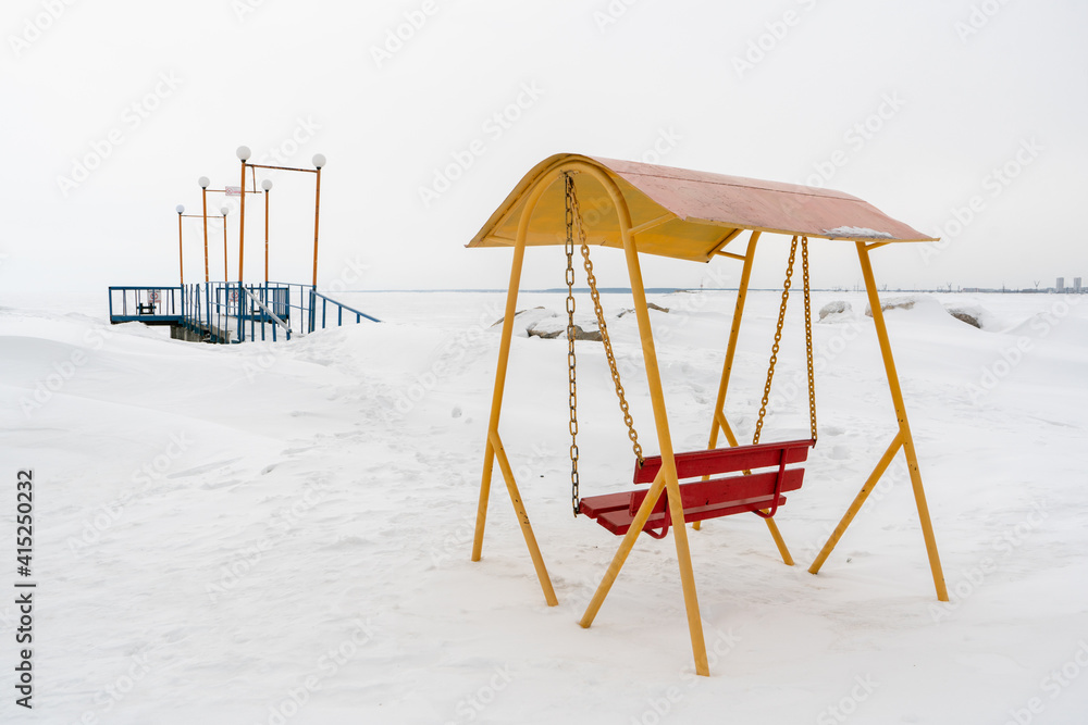 An old swing against the background of a snowy shore.. An old swing against the background of a snowy shore..
