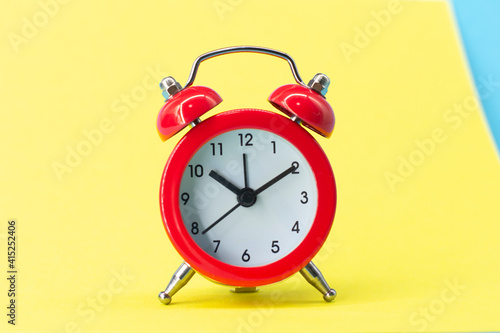 red round analog alarm clock isolated on yellow background. time 10:10. space for text.