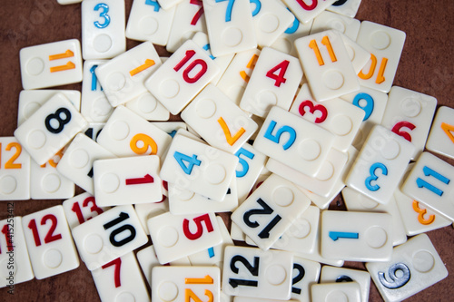 Rummi game tiles laying on a table simulating wood, in a mosaic style
