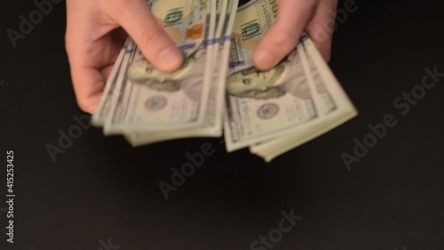 Hands are counting money. One hundred US dollar bills.