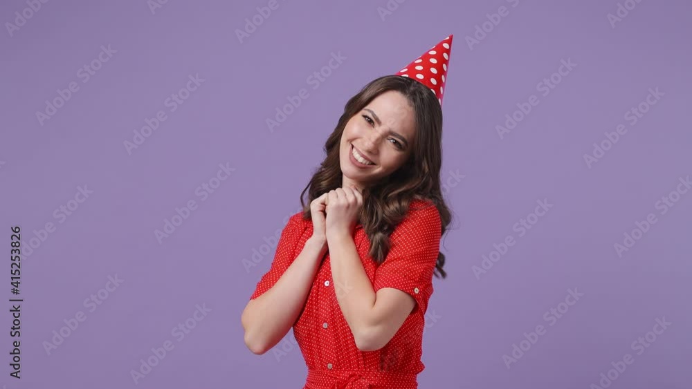 Surprised brunette young woman 20s in red dress birthday hat posing isolated on violet background in studio. Celebrating holiday party concept. Point on herself ask who me put hands on chest thanking Surprised brunette young woman 20s in red dress birthday hat posing isolated on violet background in studio. Celebrating holiday party concept. Point on herself ask who me put hands on chest thanking
