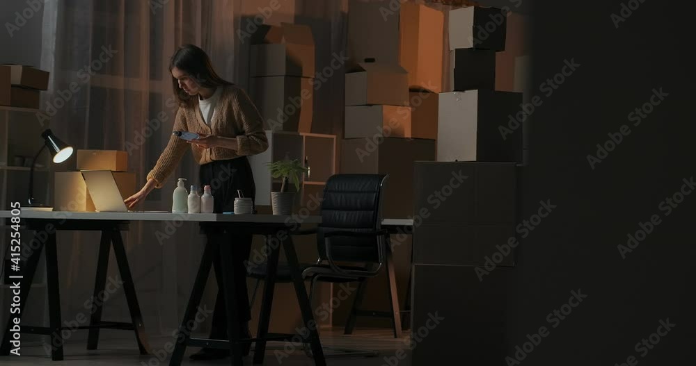 home warehouse with cosmetic boxes in apartment of young businesswoman, lady is working alone at evening home warehouse with cosmetic boxes in apartment of young businesswoman, lady is working alone at evening
