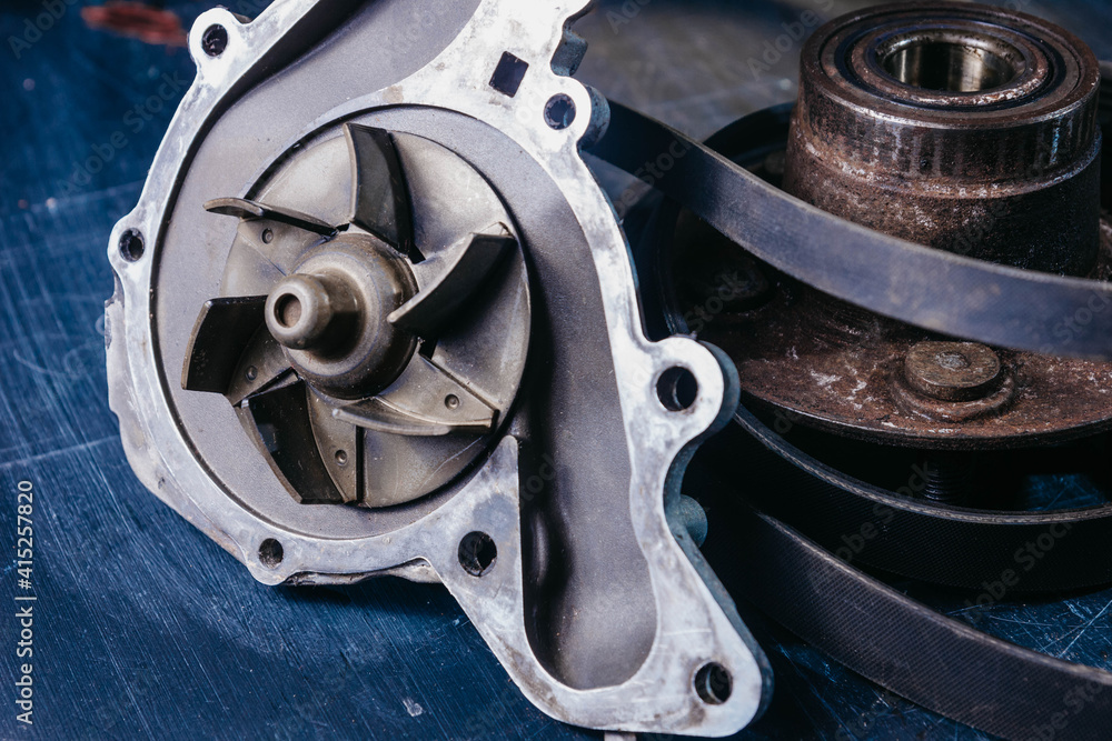 Used water pump for car engine cooling system on blue background. Used water pump for car engine cooling system on blue background.