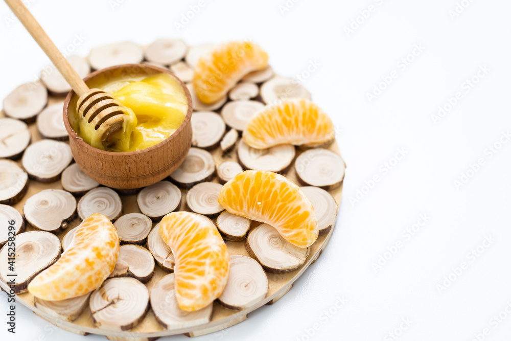 honey in a wooden bowl and orange on a white background. honey in a wooden bowl and orange on a white background.