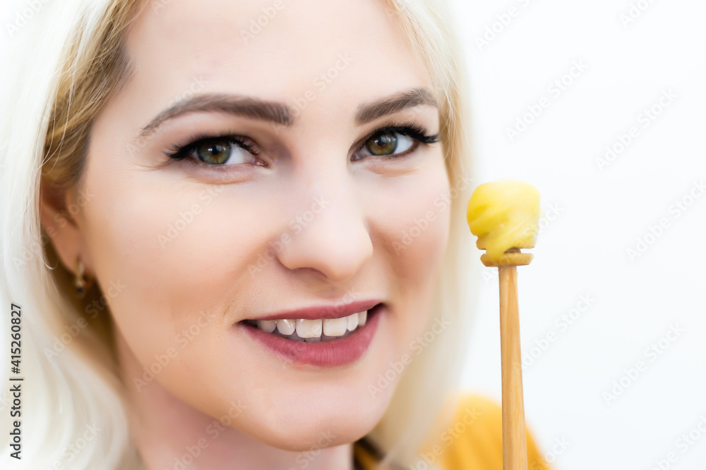 closeup of female mouth and spoon with honey on white background