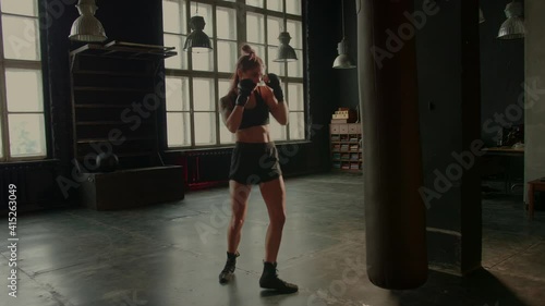 4k video of athletic female fighter exercising with punching bag in gym during kickboxing and self defense workout