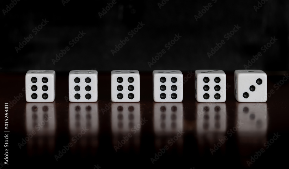 Six dice on a table with reflection and black background, five dice showing six, one dice showing three Six dice on a table with reflection and black background, five dice showing six, one dice showing three