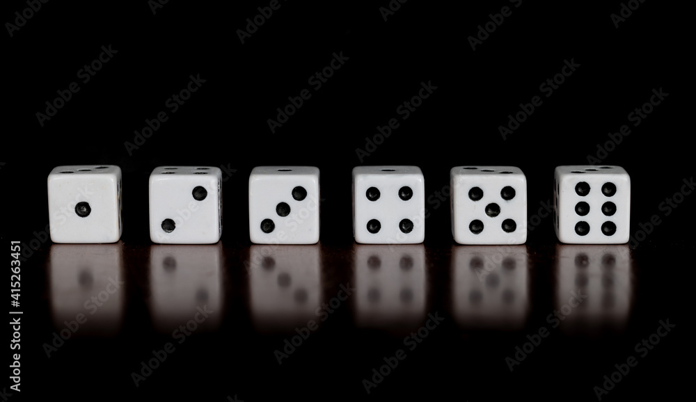 Six dice showing one through six on a table with reflection and black background Six dice showing one through six on a table with reflection and black background