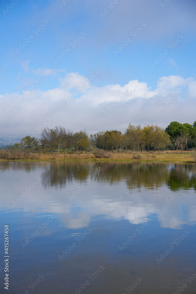 Lake dam landscape with reflection of Gardunha mountains and trees on a cloudy day in Santa Agueda Marateca Dam in Portugal