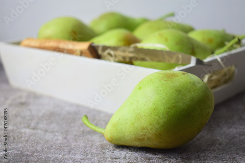 Green pear with more units at the bottom, inside a white wooden box.