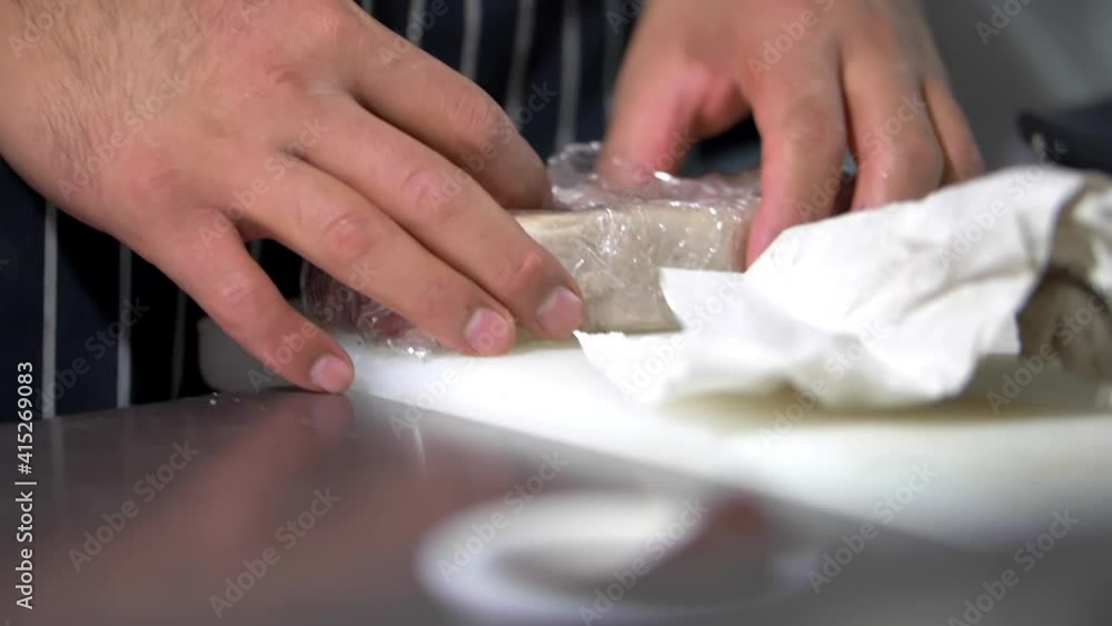 Male hands carefully unwrapping a juicy-looking piece of meat Male hands carefully unwrapping a juicy-looking piece of meat