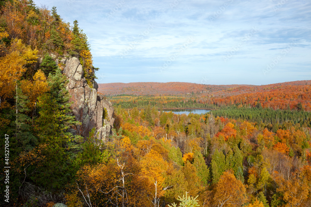 Cliff and small lake surrounded by trees in fall color in northern Minnesota