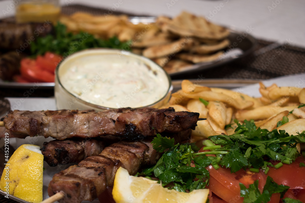.Fried souvlaki with greek salad, potatoes and tzatziki sauce in plate .Fried souvlaki with greek salad, potatoes and tzatziki sauce in plate