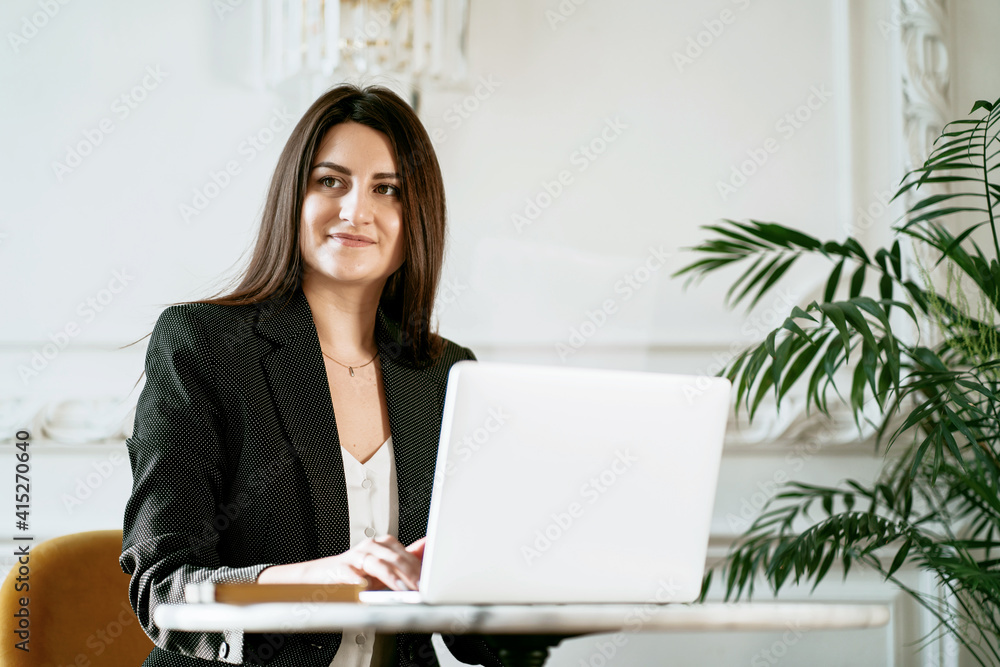 New project at work. The lawyer is sitting next to the laptop. Copy space. The Finance Manager Student beautiful brunette. A woman in a business suit. Works in a modern office. New project at work. The lawyer is sitting next to the laptop. Copy space. The Finance Manager Student beautiful brunette. A woman in a business suit. Works in a modern office.