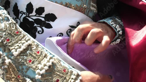 Male bullfighter hands folding a purple and red cape