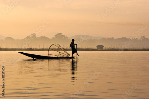 Intha leg-rowing fisherman with basket net near floating gardens on Inle Lake at sunrise  Myanmar  Burma 