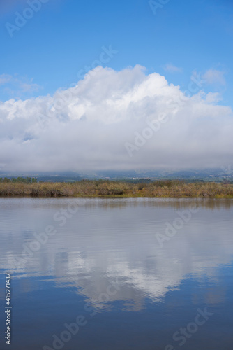 Lake dam landscape with reflection of Gardunha mountains and trees on a cloudy day in Santa Agueda Marateca Dam in Portugal