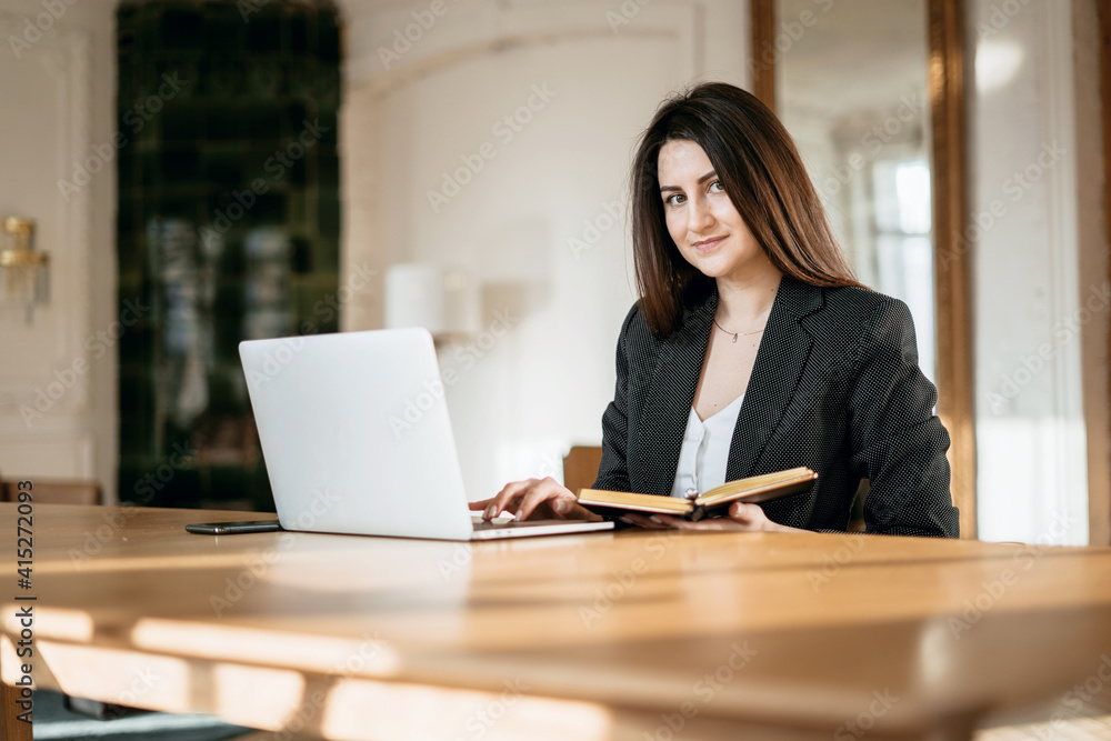 New project at work. The lawyer is sitting next to the laptop. Copy space. Accountant Manager Student beautiful brunette. A woman writes down important things. Works in a modern office.