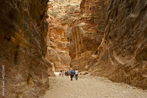 A group of tourists walks through the narrow and dramatic Siq to enter the rose red city of Petra, one of Jordan's UNESCO World Heritage Sites.