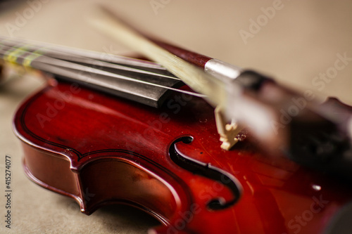 Close view of a classical small violin, strings and bridge over a beige blanket background 
