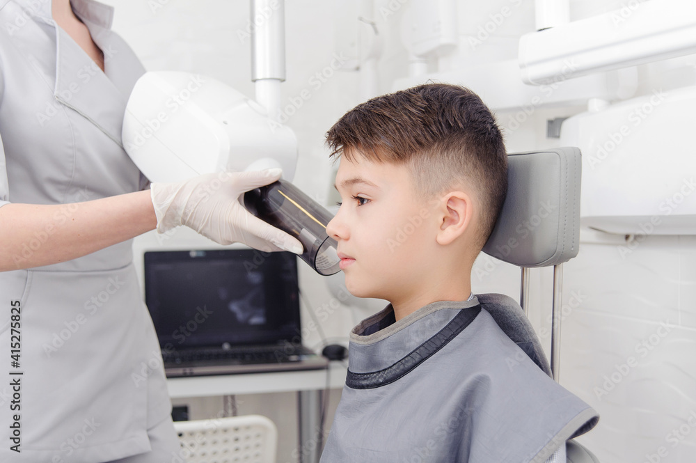 Dentist hands make jaw x-ray image for little boy in dental clinic