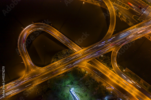 graphic drone top down shot of complex road system with interchange, traffic, bridge, ramps and loops at night over a river.