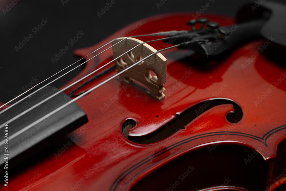 Close view of a classical small violin, strings and bridge over a beige blanket background
Close view of a classical small violin, strings and bridge over a beige blanket background