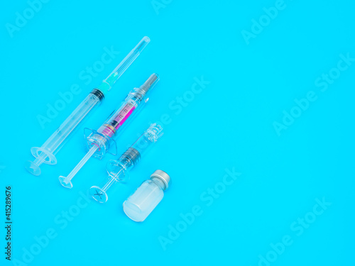 Group of syringes and vaccine on blue background. Copy space. Vaccination concept.