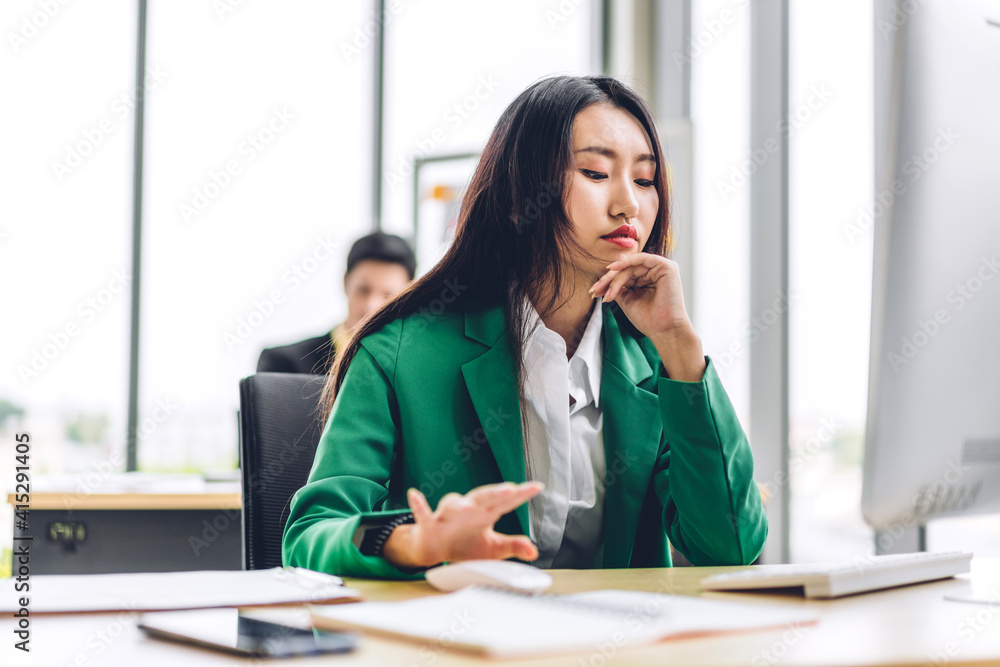 Beautiful confident asian businesswoman looking at desktop computer while sitting on office desk.Young creative coworkers business people working and planning Beautiful confident asian businesswoman looking at desktop computer while sitting on office desk.Young creative coworkers business people working and planning