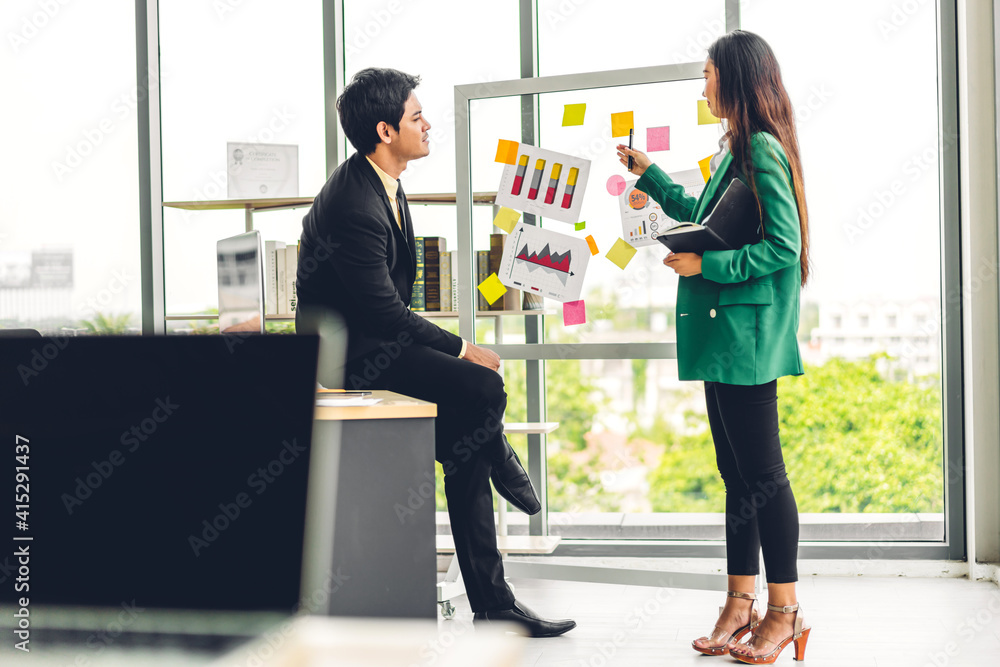 Casual creative happy two smile asian business people planning strategy analysis and brainstorm putting post it stickers note to share idea for startup project on glass board at modern office