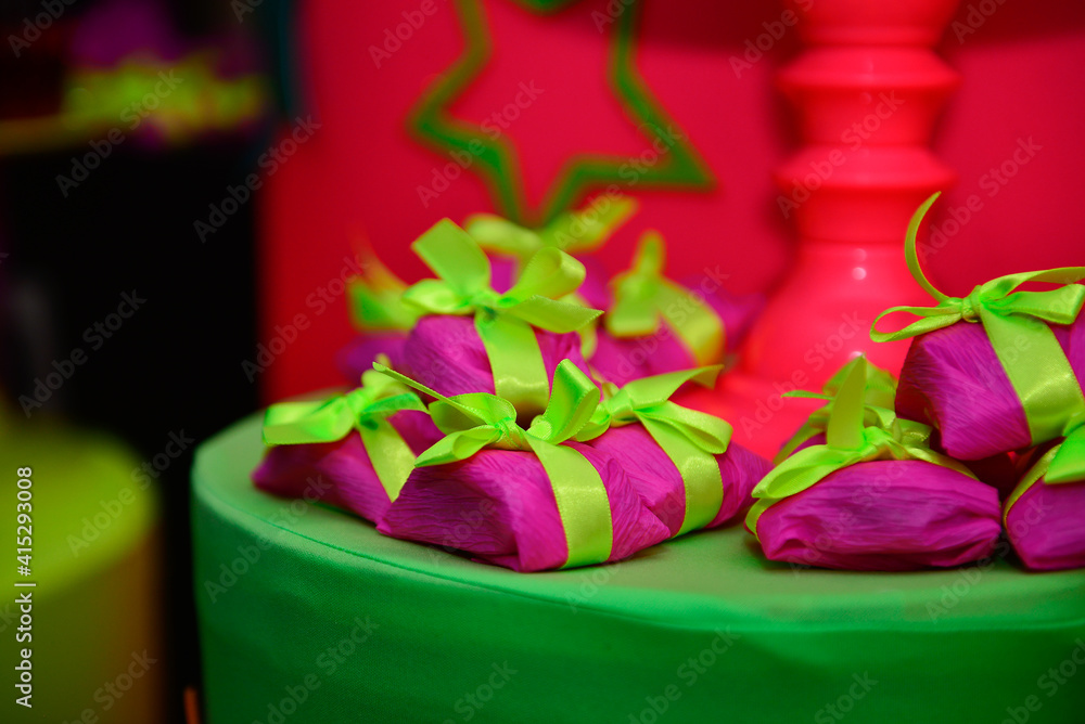 candies packed in pink paper and yellow bow on green table, birthday party, well married