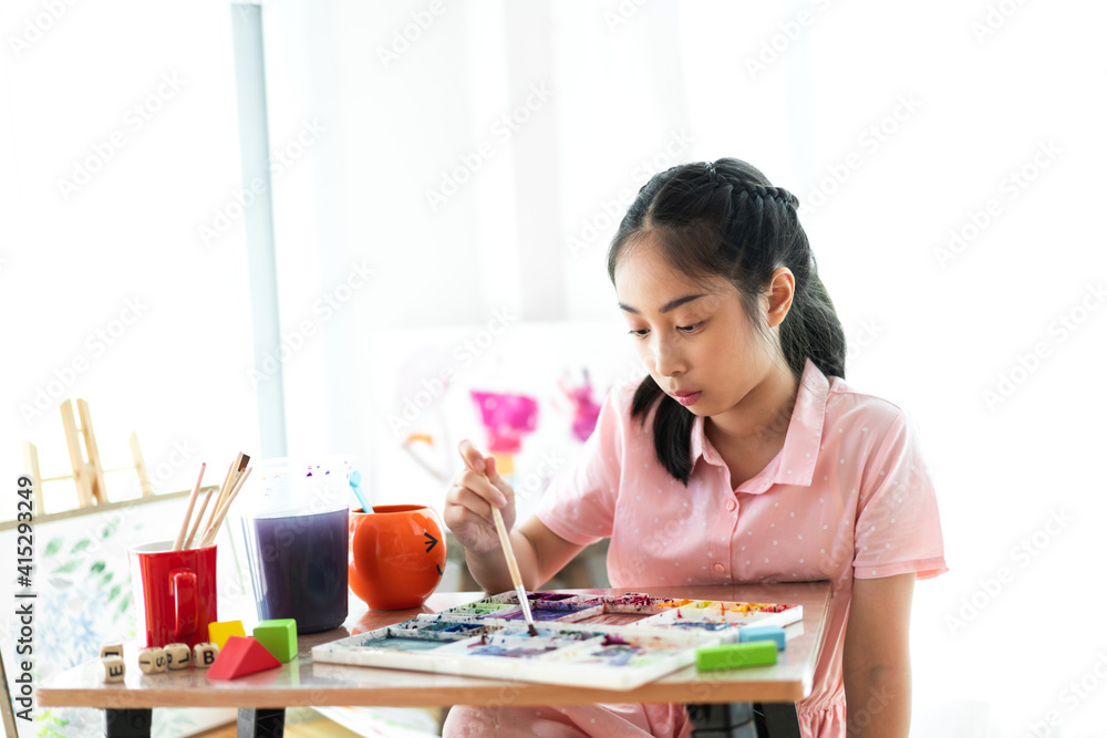 School kid little girl learning and writing in notebook with pencil making homework at home.Education concept