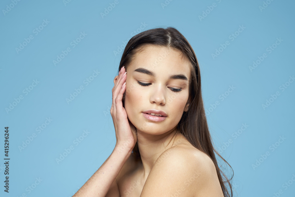 brunette with bare shoulders cosmetics close-up skin care blue background brunette with bare shoulders cosmetics close-up skin care blue background