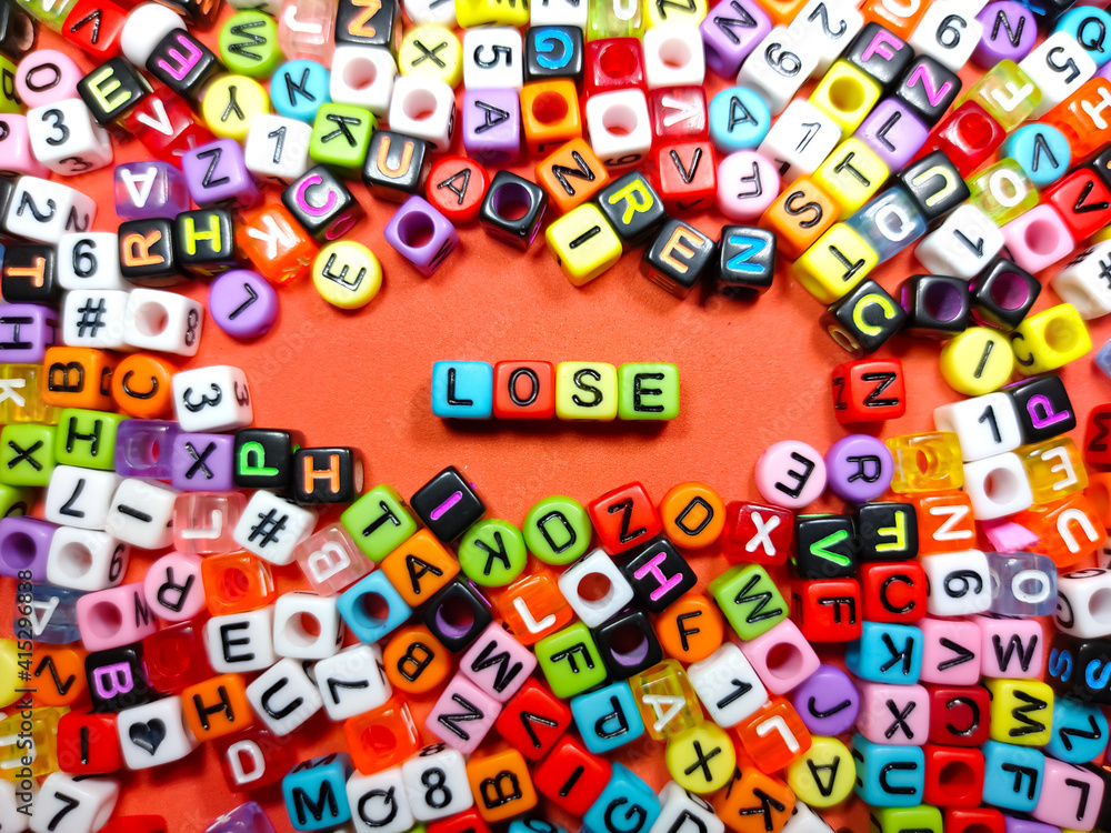 Selective focus.Colorful dice with word LOSE on red background.Shot were noise and film grain.