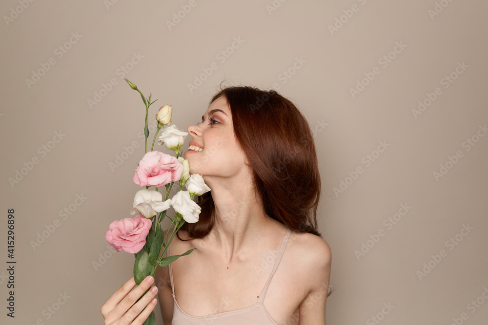 Happy woman with a bouquet of light flowers on a beige background naked shoulders model red hair beautiful face