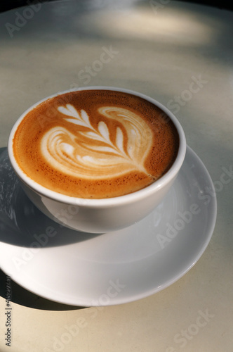 Close up hot cappuccino white coffee cup with heart shape latte art on dark brown old wood table at caff food and drink concept.