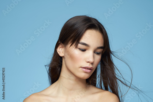 brunette with bare shoulders cosmetics close-up skin care blue background
