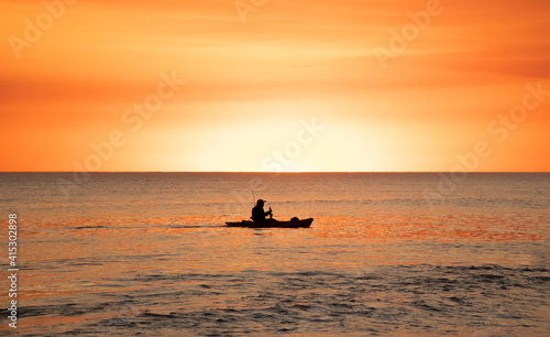 Hombre en canoa sobre atardecer © Emiliano