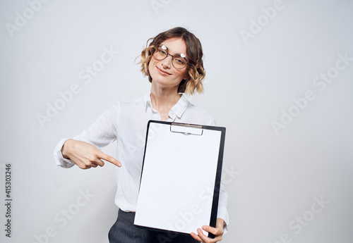 Business woman holds in her hands a folder with a white sheet on a light background