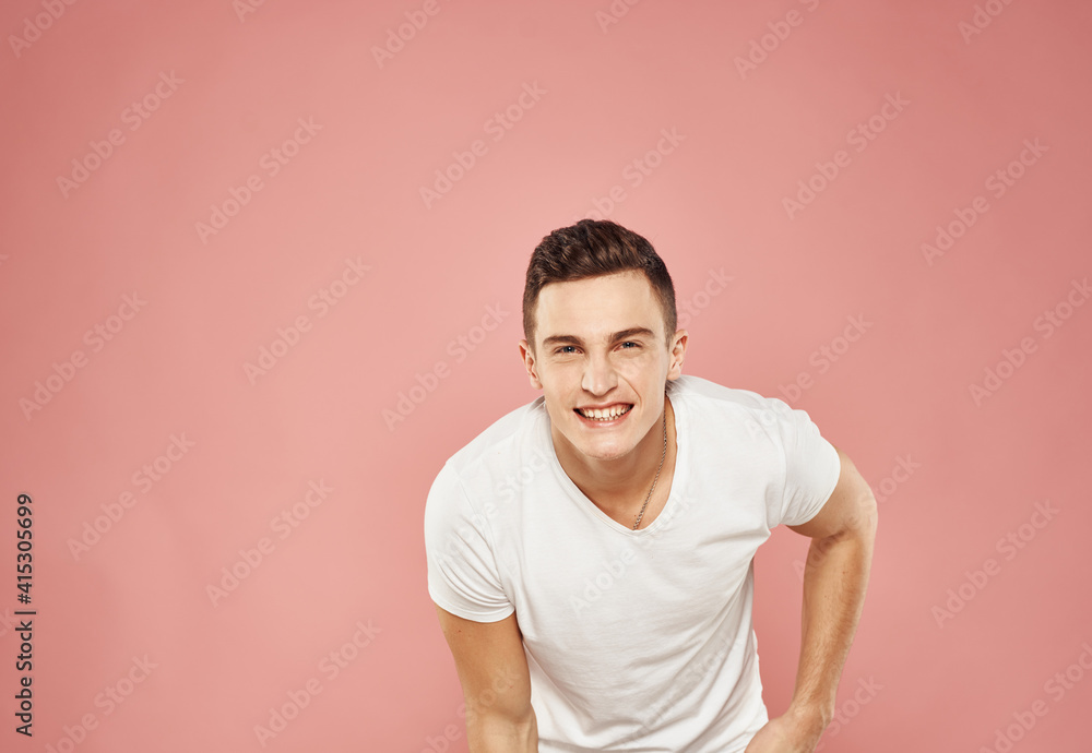 A man gestures with his hands in a white t-shirt emotions pink background A man gestures with his hands in a white t-shirt emotions pink background