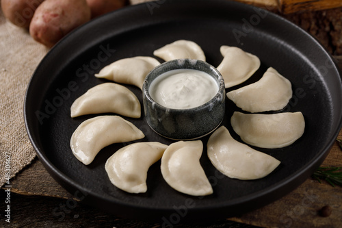 Appetizing traditional Russian dumplings, hand-made with potatoes. Still life on a wooden board. Close-up. photo