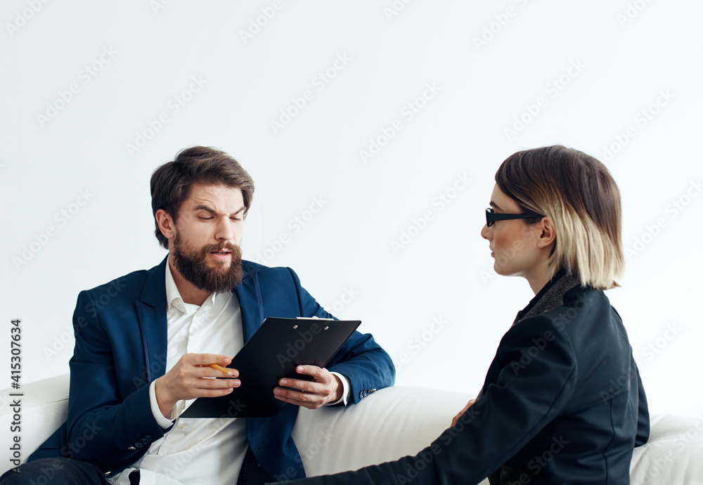 Business man and woman employees communicating on the couch indoors Business man and woman employees communicating on the couch indoors