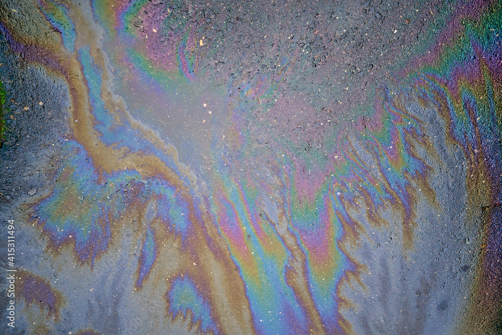 Colored oil stains in the car park, the color of the gasoline stain on the pavement road as a texture or background.