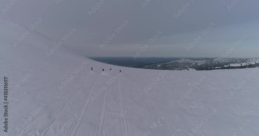 Aerial view: four snow bikers on snowmobiles ride together in a mountain valley. an epic video of a friendly team of snowmobilers riding through a large snow-white canyon high in the mountains at dawn Aerial view: four snow bikers on snowmobiles ride together in a mountain valley. an epic video of a friendly team of snowmobilers riding through a large snow-white canyon high in the mountains at dawn