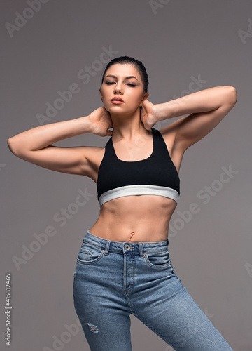 Fashion glamour teenager girl model beauty studio portrait isolated on grey background. Charming young woman wearing black crop top, jeans. Teenage vogue. Carefree youth