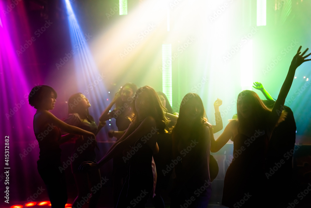 Fototapeta Silhouette image of people dance in disco night club to music from DJ on stage . New year night party and nightlife concept .