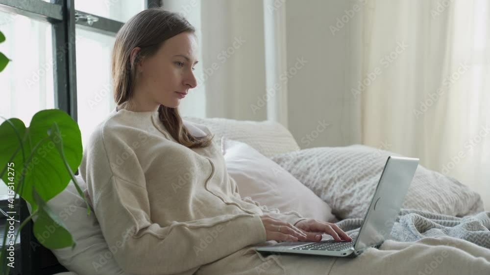Relaxed brunette young woman using laptop in bed at home Relaxed brunette young woman using laptop in bed at home