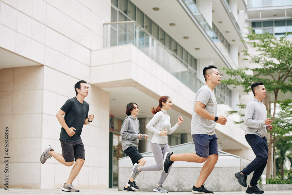 Young Asian people running on street in the morning, training for half marathon